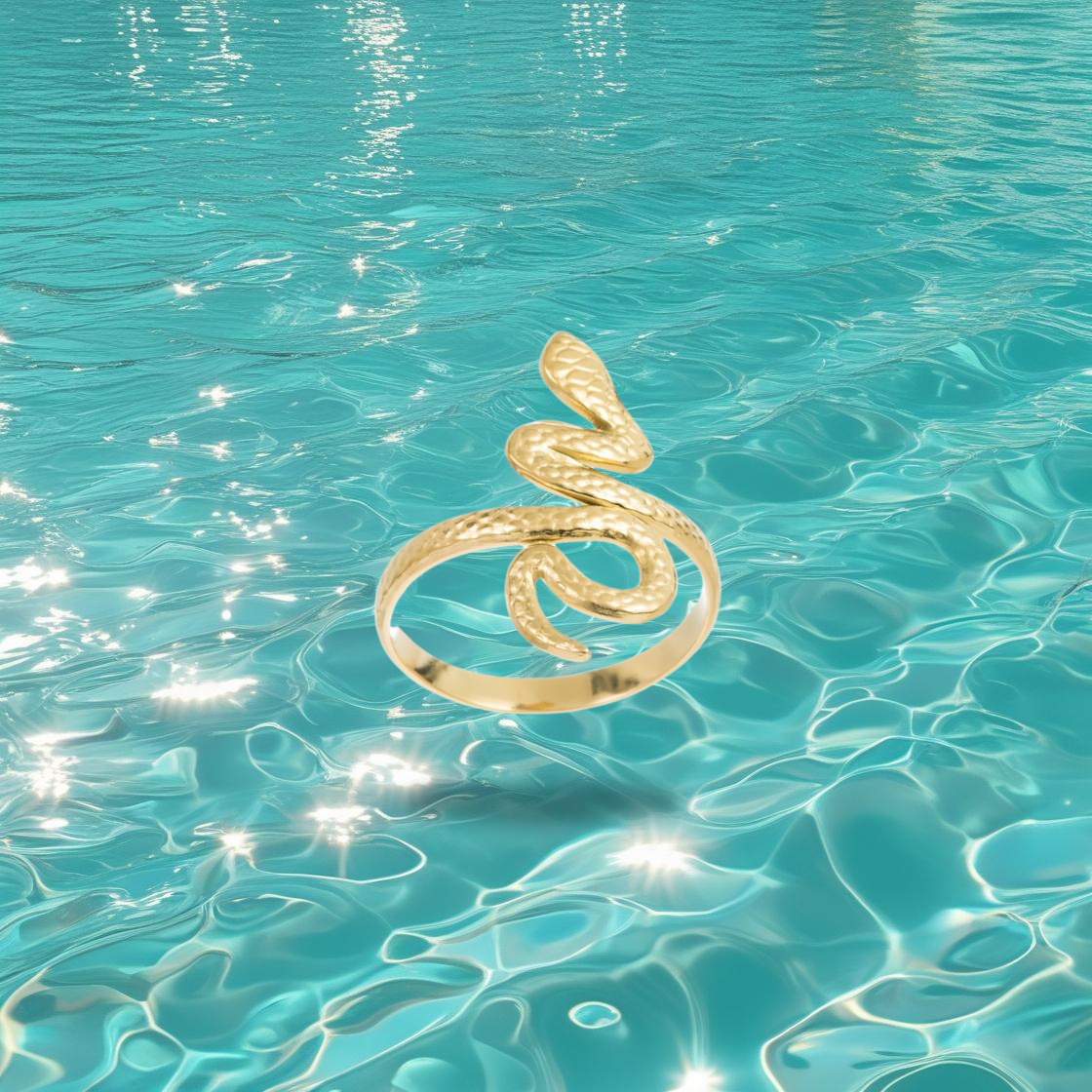 Bague Timin dorée en forme de serpent, style égyptien, photographiée sur un fond marin.