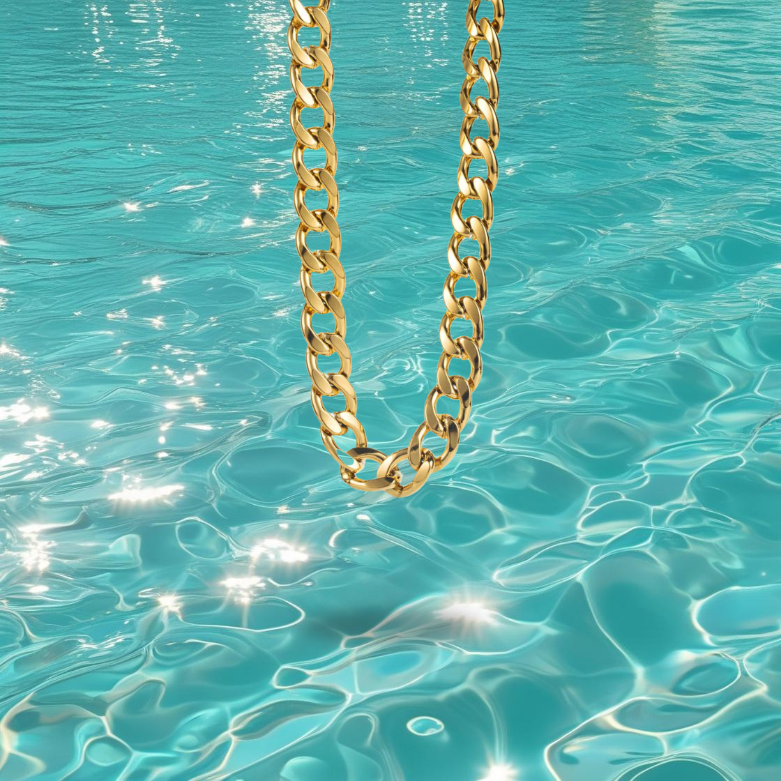 Collier Vanela Bahari en acier inoxydable doré à gros maillons type gourmette, photographié devant la mer