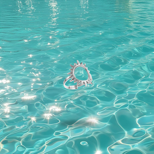 Bague Barna Bahari en acier inoxydable argent en forme de soleil, photographiée devant la mer