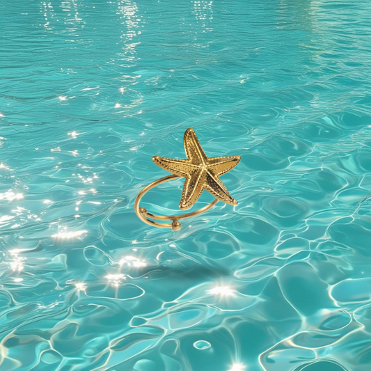 Bague Najma dorée réglable en forme d’étoile de mer, présentée sur un fond marin.