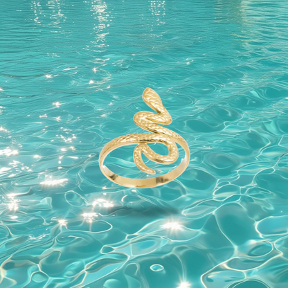 Bague Timin dorée en forme de serpent, style égyptien, photographiée sur un fond marin.