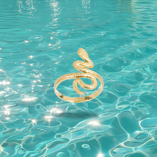 Bague Timin dorée en forme de serpent, style égyptien, photographiée sur un fond marin.