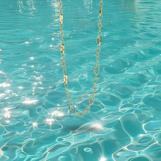 Collier Lorena Bahari en acier inoxydable doré à maillons ovales fins, photographié devant la mer