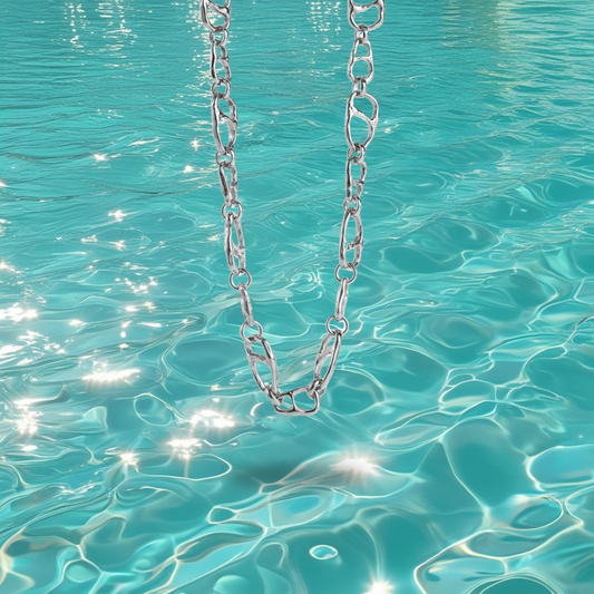 Collier Mahei Bahari en acier inoxydable argent à maillons irréguliers, photographié devant la mer