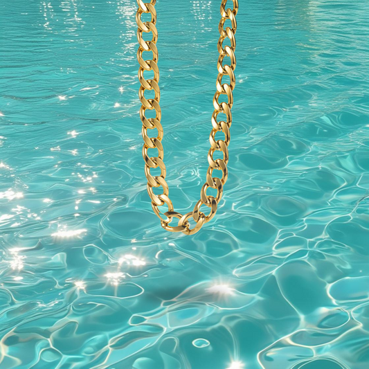 Collier Vanela Bahari en acier inoxydable doré à gros maillons type gourmette, photographié devant la mer